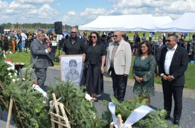 Uczestnicy uroczystości upamiętniającej zagładę Romów i Sinti składają wieniec przy pomniku w byłym obozie Auschwitz II-Birkenau. W tle widoczne namioty, zgromadzeni goście i przedstawiciele władz.