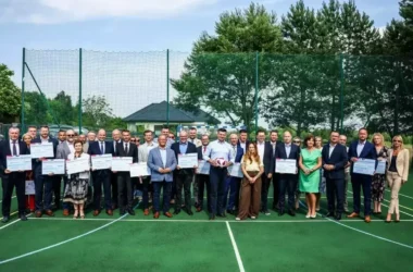 Przedstawiciele małopolskich samorządów z promesami Małopolskiego Programu Rozwoju Bazy Sportowej 2025, wręczonymi przez marszałka województwa na boisku. Kęty