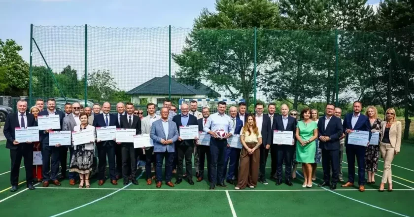 Przedstawiciele małopolskich samorządów z promesami Małopolskiego Programu Rozwoju Bazy Sportowej 2025, wręczonymi przez marszałka województwa na boisku. Kęty