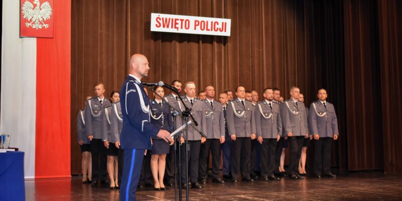 Funkcjonariusze Policji podczas uroczystości Święta Policji 2025 w Oświęcimskim Centrum Kultury – wręczanie awansów i odznaczeń przez komendanta, w tle sztandar Komendy Powiatowej Policji w Oświęcimiu.