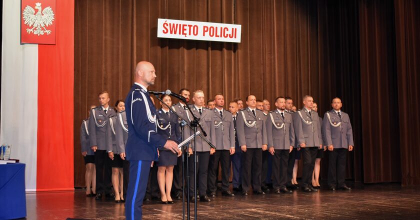 Funkcjonariusze Policji podczas uroczystości Święta Policji 2025 w Oświęcimskim Centrum Kultury – wręczanie awansów i odznaczeń przez komendanta, w tle sztandar Komendy Powiatowej Policji w Oświęcimiu.