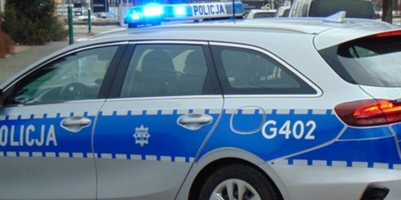 adiowóz Komendy Powiatowej Policji w Oświęcimiu z włączonymi niebieskimi sygnałami świetlnymi