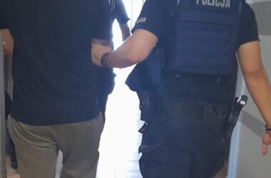 Policjant z Komisariatu Policji w Zatorze prowadzi zatrzymanego 31-letniego mężczyznę, podejrzanego o znęcanie się nad matką i usiłowanie rozboju. Zatrzymanie nastąpiło po domowej awanturze, która ujawniła wieloletnią przemoc psychiczną i fizyczną wobec 54-letniej kobiety.