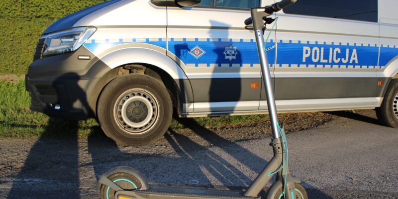Hulajnoga elektryczna stojąca przed radiowozem policyjnym – interwencja policji w sprawie nieletnich użytkowników hulajnóg w powiecie oświęcimskim.