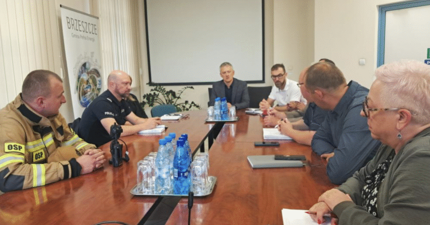 Posiedzenie Sztabu Kryzysowego Gminy Brzeszcze 28 lipca 2025 r. — przy stole obrad zasiadają przedstawiciele straży pożarnej, policji, urzędu gminy oraz innych służb. W tle baner promujący gminę Brzeszcze.
