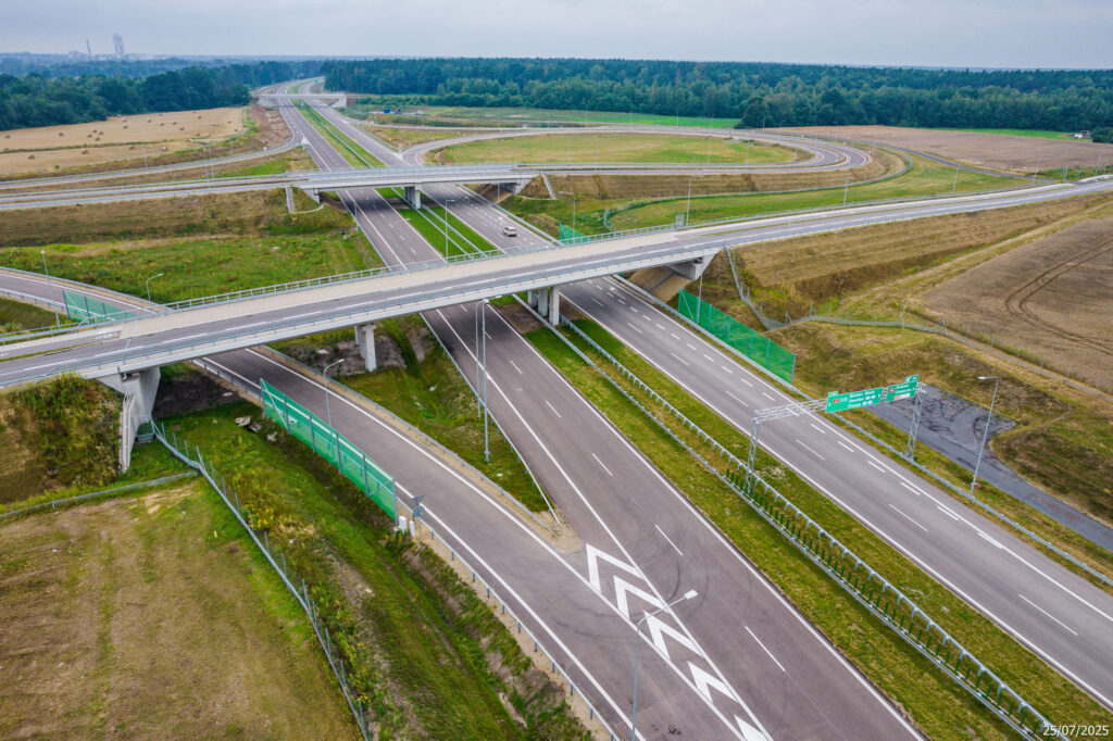 Nowo wybudowany węzeł drogowy na drodze ekspresowej S-1 w pobliżu Oświęcimia, widziany z lotu ptaka. Zdjęcie przedstawia skrzyżowanie wielopoziomowe z nowoczesnymi jezdniami, barierami energochłonnymi, ekranami akustycznymi i oznakowaniem kierunkowym. Otoczenie stanowią pola uprawne i lasy. Data wykonania zdjęcia: 25 lipca 2025 roku.