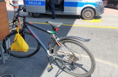 Rower stojący przy stojaku obok stacji paliw w Oświęcimiu, w tle radiowóz policyjny i funkcjonariusz