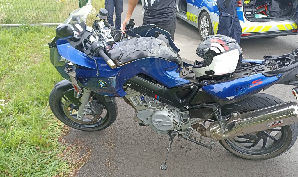 Uszkodzony motocykl BMW F800S po wypadku w Bielanach, obok policjanci i radiowóz policyjny