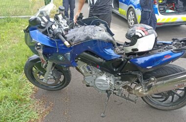 Uszkodzony motocykl BMW F800S po wypadku w Bielanach, obok policjanci i radiowóz policyjny