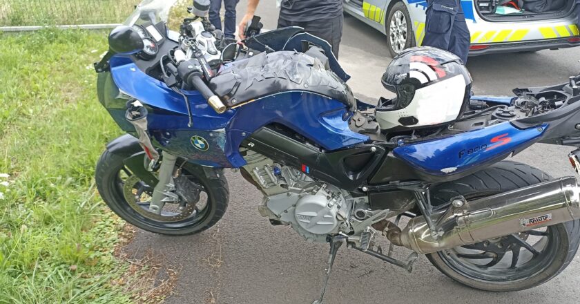 Uszkodzony motocykl BMW F800S po wypadku w Bielanach, obok policjanci i radiowóz policyjny