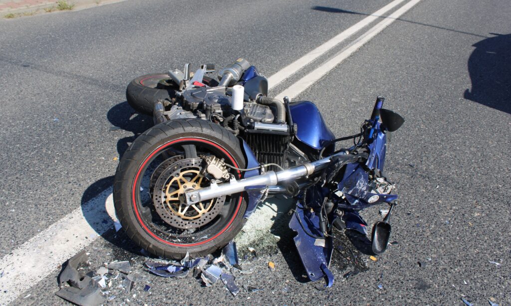 Rozbity motocykl leży na jezdni po wypadku drogowym w Rajsku – widoczne uszkodzenia maszyny i rozrzucone odłamki plastiku.