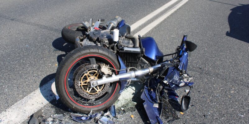 Rozbity motocykl leży na jezdni po wypadku drogowym w Rajsku – widoczne uszkodzenia maszyny i rozrzucone odłamki plastiku.