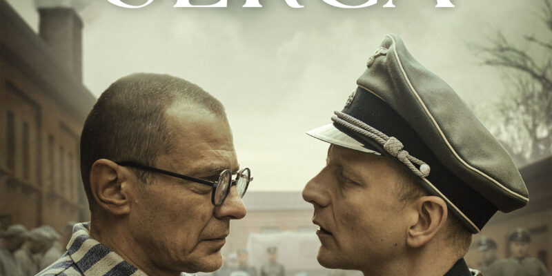 Plakat filmu „Triumf serca” przedstawiający scenę twarzą w twarz między więźniem obozu koncentracyjnego w pasiaku (w którego wciela się Marcin Kwaśny) a oficerem SS. W tle widoczny obozowy krajobraz. Na górze widnieje tytuł filmu „Triumf serca” oraz nazwiska głównych aktorów: Marcin Kwaśny, Rowan Polonski, Christopher Sherwood. Na dole umieszczono informację „W kinach od 12 września” wraz z logotypami producentów.