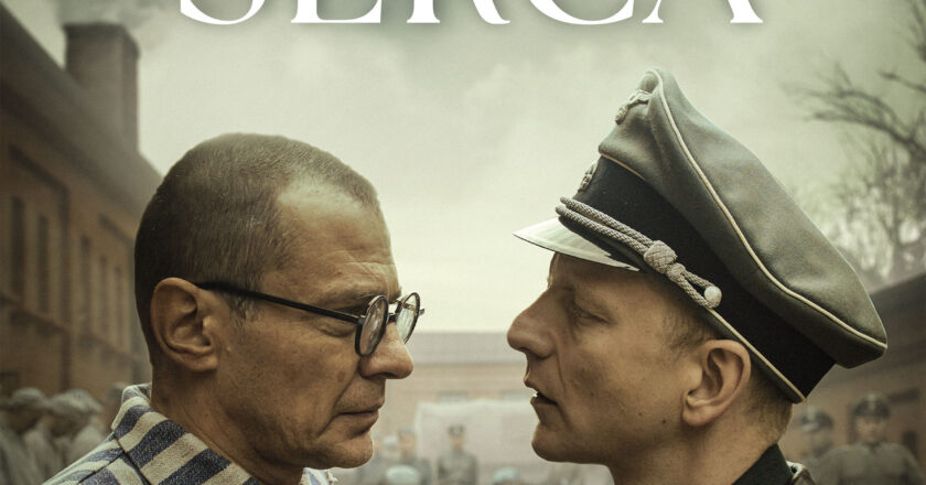 Plakat filmu „Triumf serca” przedstawiający scenę twarzą w twarz między więźniem obozu koncentracyjnego w pasiaku (w którego wciela się Marcin Kwaśny) a oficerem SS. W tle widoczny obozowy krajobraz. Na górze widnieje tytuł filmu „Triumf serca” oraz nazwiska głównych aktorów: Marcin Kwaśny, Rowan Polonski, Christopher Sherwood. Na dole umieszczono informację „W kinach od 12 września” wraz z logotypami producentów.