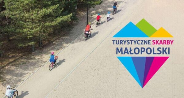 Grupa rowerzystów jadących ścieżką wśród drzew, logo konkursu Turystyczne Skarby Małopolski z kolorowym motywem gór.