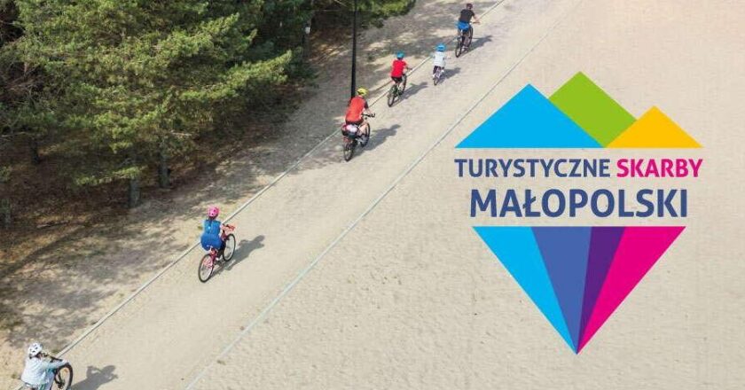 Grupa rowerzystów jadących ścieżką wśród drzew, logo konkursu Turystyczne Skarby Małopolski z kolorowym motywem gór.