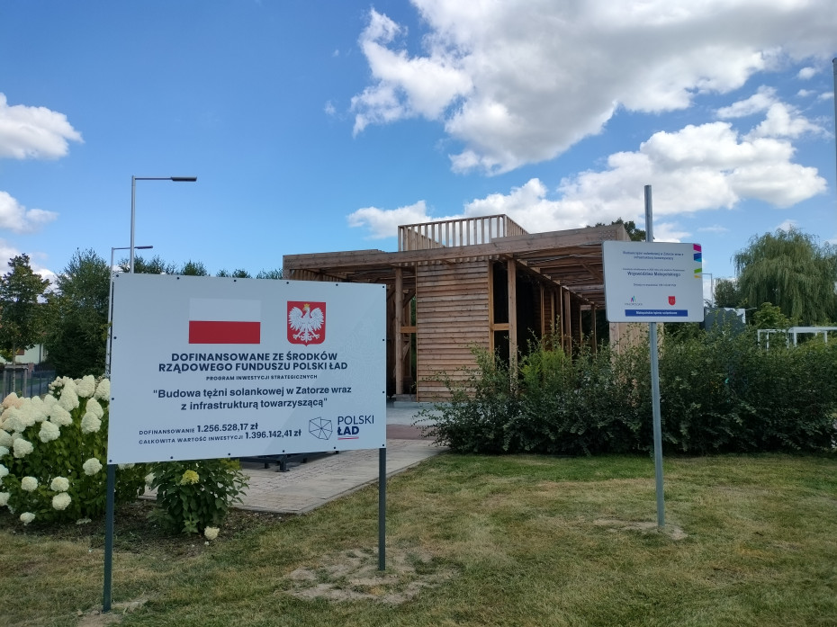Drewniana tężnia solankowa w Zatorze przy ul. Słowackiego, wyposażona w ściany z tarniny i zadaszoną strefę inhalacyjną z ławkami dla odwiedzających.