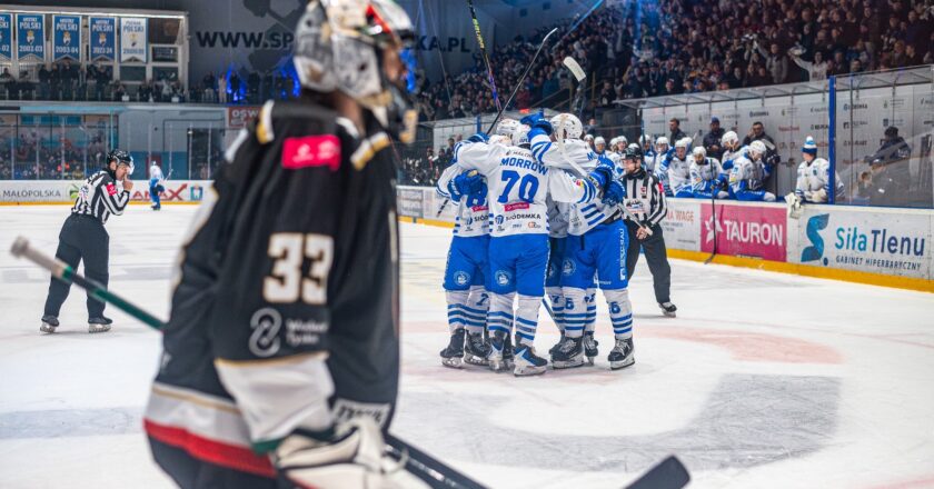 Hokeiści Unii Oświęcim świętują zdobycie bramki podczas meczu z GKS Tychy w TAURON Hokej Lidze. W tle kibice na trybunach, a na pierwszym planie bramkarz drużyny gości.