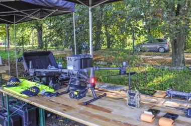 Nowoczesny dron DJI Matrice 350 RTK z kamerą Zenmuse H30T na stole wraz z wyposażeniem Straży Miejskiej w Kętach, używany do kontroli jakości powietrza i walki ze smogiem.