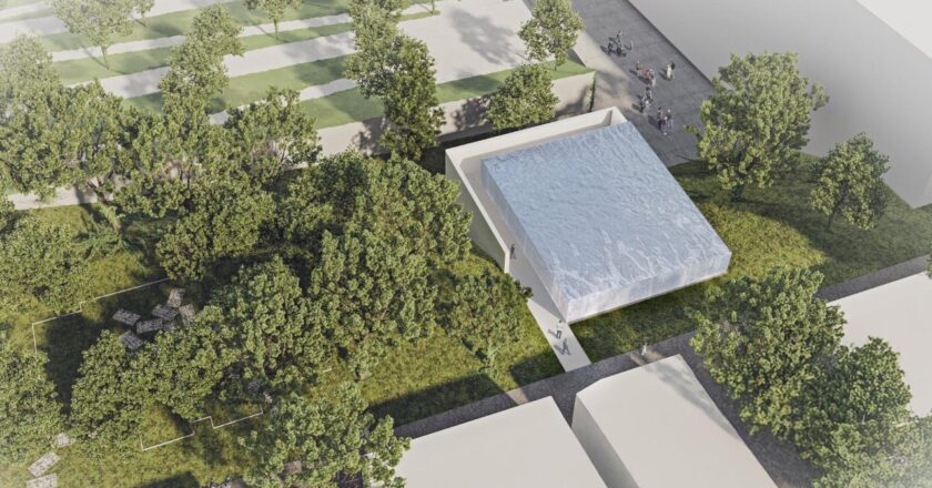 Wizualizacja pawilonu ekspozycyjnego przy Parku Pamięci Wielkiej Synagogi w Oświęcimiu, otoczonego zielenią i ścieżkami, z widoczną nowoczesną, jasną bryłą budynku przeznaczonego do prezentacji XVIII-wiecznej mykwy.