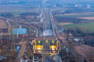Widok z drona na budowę obwodnicy Oświęcimia: powstający tunel pod torami kolejowymi oraz długi odcinek nowej drogi przebiegającej przez tereny rolnicze w rejonie Brzezinki.
