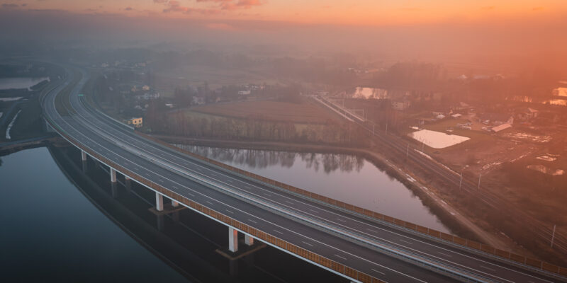 Nowy odcinek drogi ekspresowej S1 w rejonie Oświęcimia i Brzeszcz, widok z lotu ptaka na estakadę nad rzeką o wschodzie słońca, oddany do ruchu w grudniu 2025 roku.
