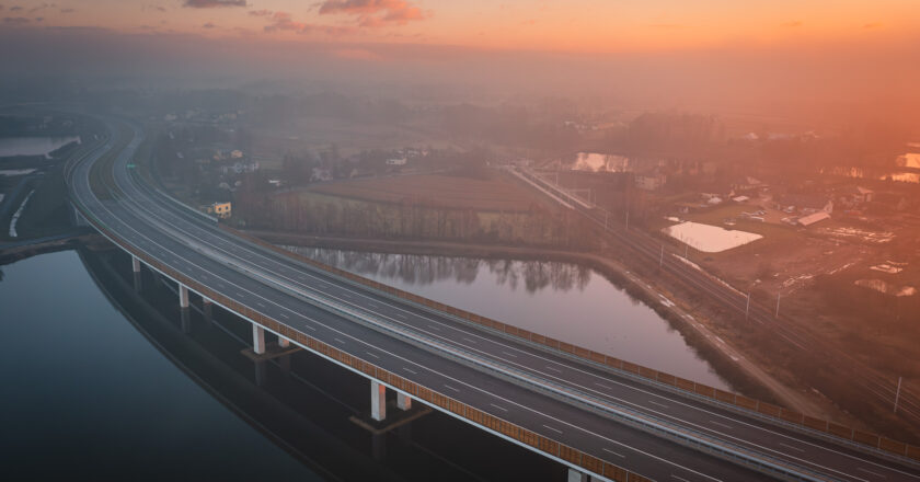 Nowy odcinek drogi ekspresowej S1 w rejonie Oświęcimia i Brzeszcz, widok z lotu ptaka na estakadę nad rzeką o wschodzie słońca, oddany do ruchu w grudniu 2025 roku.