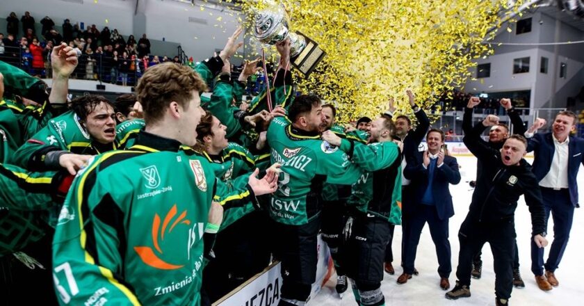 Hokeiści JKH GKS Jastrzębie świętują zdobycie TAURON Pucharu Polski – zawodnicy w zielonych strojach unoszą trofeum w górę, a nad lodowiskiem unoszą się złote konfetti po finale w Krynicy-Zdroju.