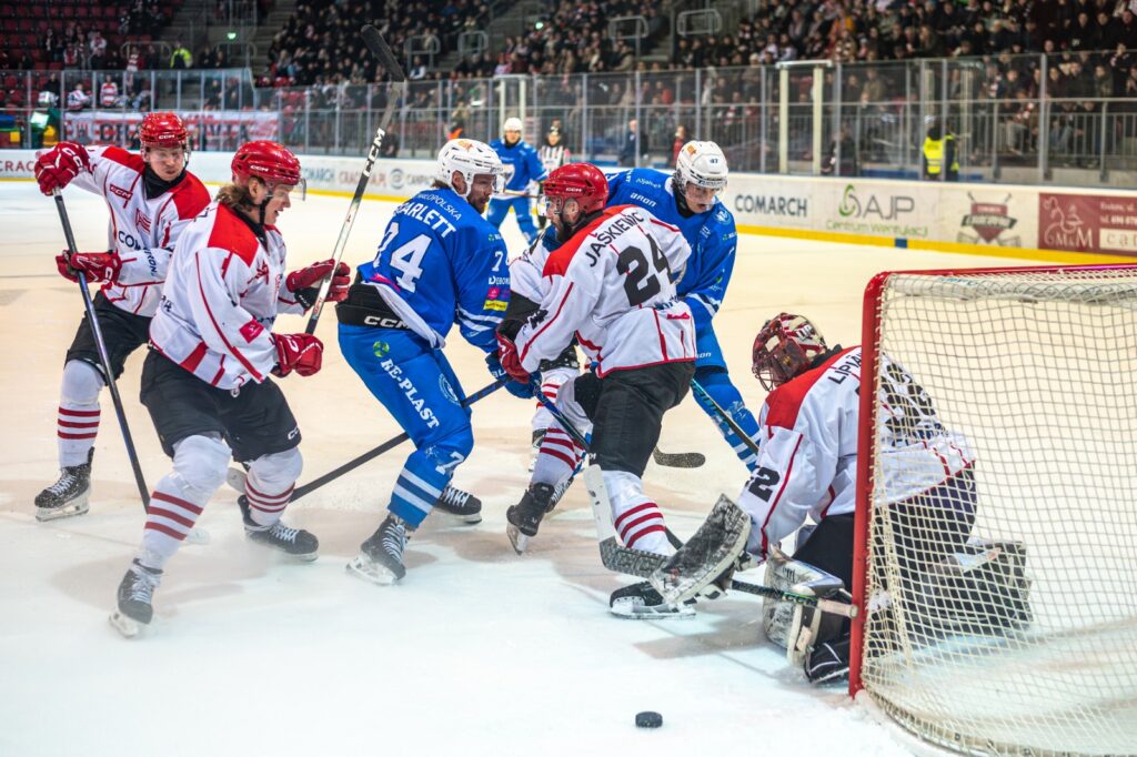 Zawodnicy Cracovii i Unii Oświęcim walczą o krążek przed bramką gospodarzy podczas meczu hokejowego; bramkarz interweniuje w chaosie podbramkowym. Foto: Jarosław Fiedor / Unia Oświęcim.