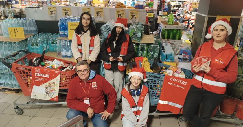Wolontariusze Caritas Diecezji Bielsko-Żywieckiej podczas zbiórki „Tak Pomagam” w sklepie – młodzież i opiekun w czerwonych kamizelkach Caritas stoją przy koszach wypełnionych żywnością, zbieraną dla osób potrzebujących.