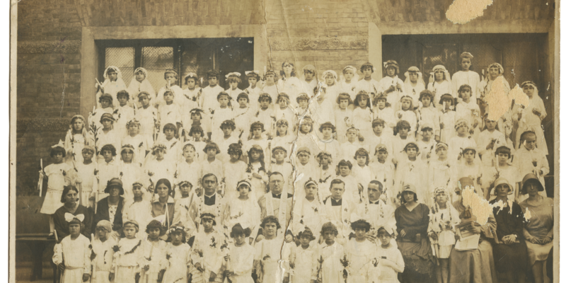 Pamiątka I komunii  świętej Zofii Daczyńskiej. Fotografia została wykonana 23 czerwca 1930 roku w Oświęcimiu. W środku, w okularach charyzmatyczny ksiądz Jan Skarbek. Fot. Zbiory Muzeum Pamięci Mieszkańców Ziemi Oświęcimskiej/Dar Bogumiły Stachury