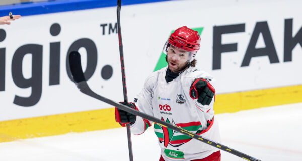 Zawodnik hokejowy ECB Zagłębie Sosnowiec w białym stroju cieszy się po zdobyciu bramki, wskazując kijem w kierunku trybun podczas meczu TAURON Pucharu Polski.