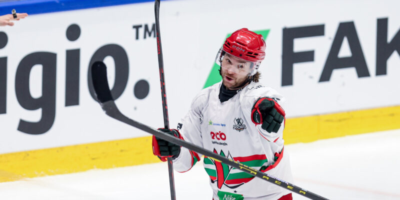 Zawodnik hokejowy ECB Zagłębie Sosnowiec w białym stroju cieszy się po zdobyciu bramki, wskazując kijem w kierunku trybun podczas meczu TAURON Pucharu Polski.