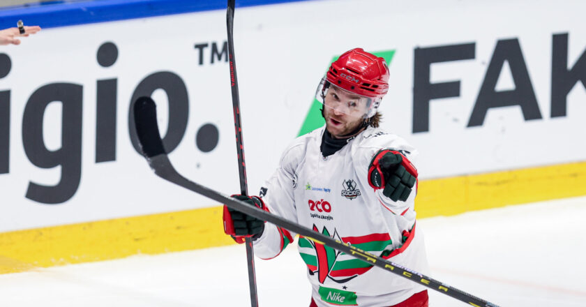 Zawodnik hokejowy ECB Zagłębie Sosnowiec w białym stroju cieszy się po zdobyciu bramki, wskazując kijem w kierunku trybun podczas meczu TAURON Pucharu Polski.