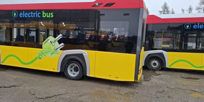Nowoczesny autobus elektryczny marki Solaris zaparkowany na terenie zajezdni Miejskiego Zakładu Komunikacji w Oświęcimiu, z charakterystycznym oznaczeniem „electric bus” i grafiką zielonej wtyczki symbolizującą zeroemisyjny transport.