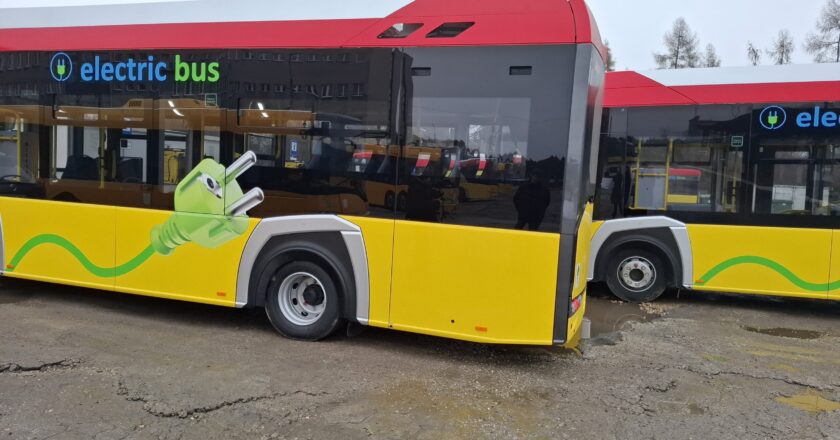 Nowoczesny autobus elektryczny marki Solaris zaparkowany na terenie zajezdni Miejskiego Zakładu Komunikacji w Oświęcimiu, z charakterystycznym oznaczeniem „electric bus” i grafiką zielonej wtyczki symbolizującą zeroemisyjny transport.