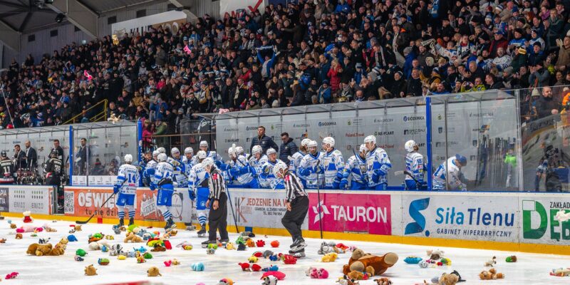 Kibice Unii Oświęcim wypełniający trybuny lodowiska podczas meczu, a na tafli dziesiątki pluszowych misiów rzuconych w ramach akcji Teddy Bear Toss.