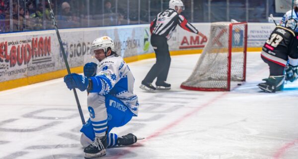Hokeista Unii Oświęcim cieszący się po zdobytej bramce podczas meczu Tauron Hokej Ligi, w tle bramka i sędzia na lodowisku