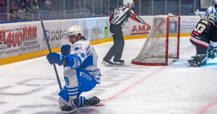 Hokeista Unii Oświęcim cieszący się po zdobytej bramce podczas meczu Tauron Hokej Ligi, w tle bramka i sędzia na lodowisku