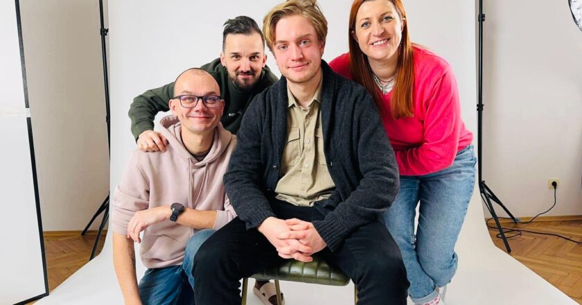 Uczestnicy projektu „Stories That Move” podczas nagrań w studiu – czworo młodych dorosłych siedzących i stojących przed białym tłem fotograficznym, uśmiechnięci, w nieformalnej atmosferze, przygotowani do realizacji materiałów edukacyjnych.