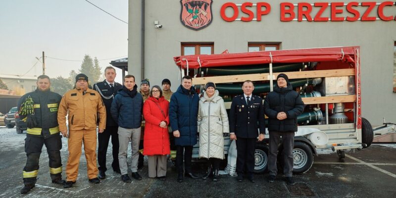Przekazanie nowego sprzętu dla OSP Brzeszcze – strażacy ochotnicy i przedstawiciele samorządu przed remizą z agregatem pompowym i wyposażeniem ratowniczym