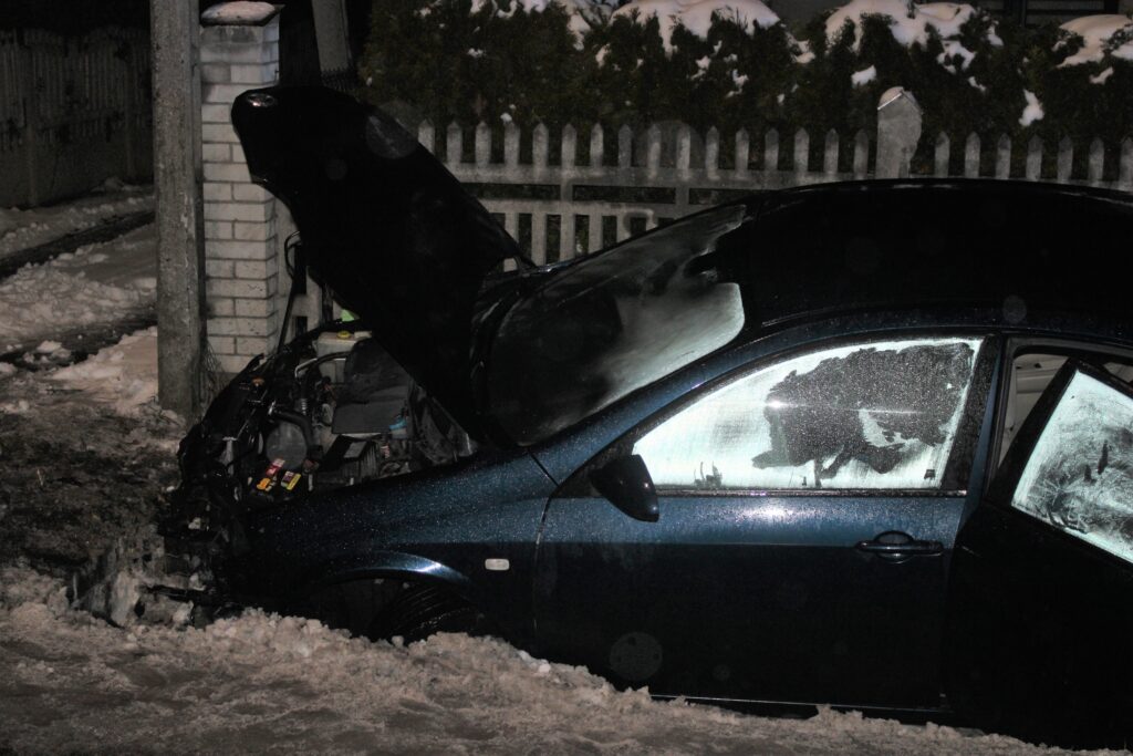 Uszkodzony samochód osobowy po wypadku drogowym w Osieku – auto w rowie przy posesji, nocne warunki, widoczne zniszczenia przodu pojazdu i otwarta maska.