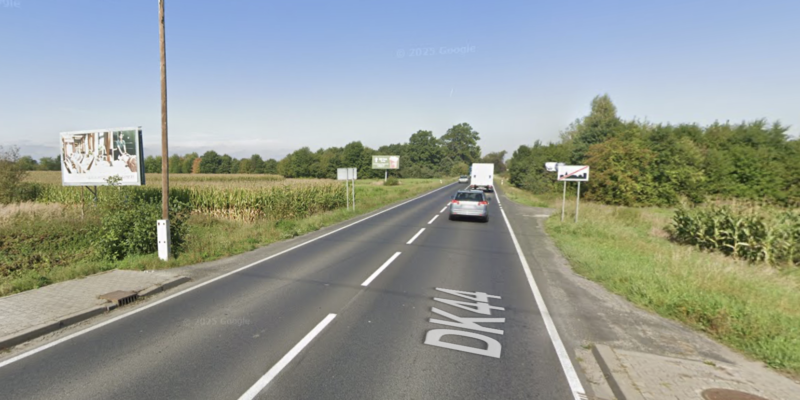 Droga krajowa nr 44 na odcinku między Bieruniem a Babicami – dwupasmowa jezdnia bez chodnika i ścieżki rowerowej, otoczona polami, z intensywnym ruchem samochodowym i brakiem bezpiecznej infrastruktury dla pieszych.