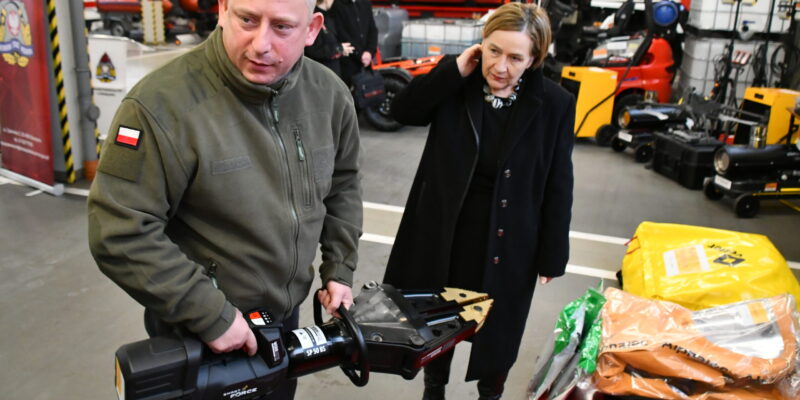 Prezentacja nowoczesnego sprzętu ratowniczego w Komendzie Powiatowej PSP w Oświęcimiu – strażak demonstruje hydrauliczne narzędzie ratownicze, obok przedstawicielka władz oglądająca wyposażenie zakupione w ramach Programu Ochrony Ludności i Obrony Cywilnej.