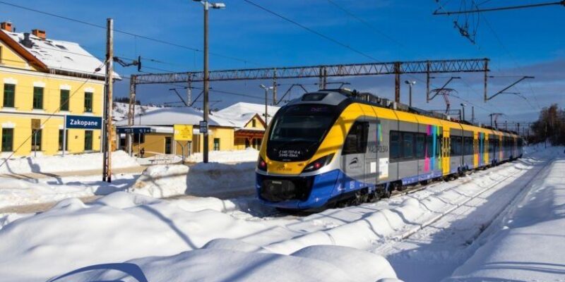 Pociąg Kolei Małopolskich kursujący zimą na stacji kolejowej w Zakopanem – skład regionalny na ośnieżonych torach w Małopolsce.