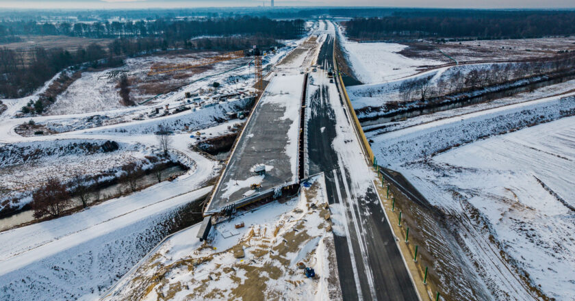 Budowa trasy S1 w rejonie węzła Bieruń zimą – widok z lotu ptaka na most nad Gostynią i nowy odcinek drogi w trakcie realizacji