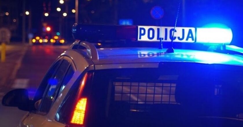 Radiowóz Policji z włączonymi niebieskimi światłami uprzywilejowania nocą na ulicy – interwencja policyjna w powiecie oświęcimskim.