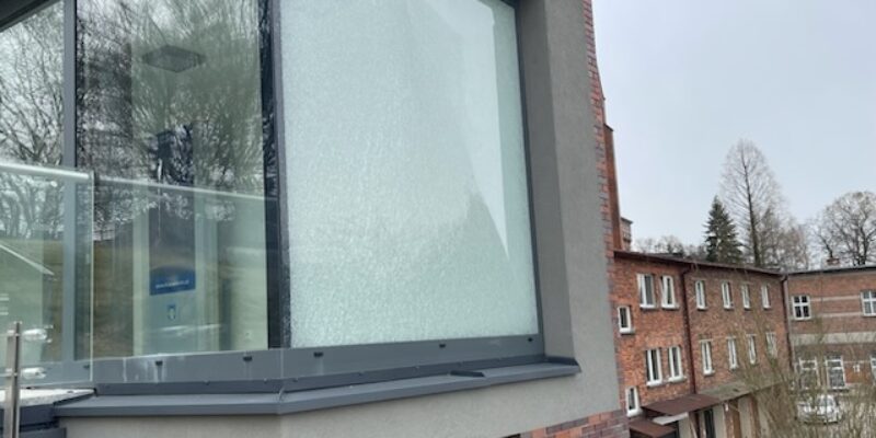 Uszkodzona szklana szyba w części socjalnej parkingu przy ul. Bulwary w Oświęcimiu – skutek aktu wandalizmu